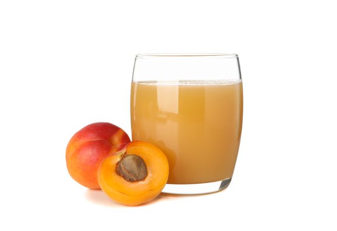 Glass with juice and apricots isolated on plain background