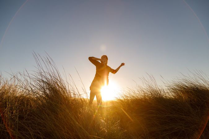 Woman posing between field at sunset