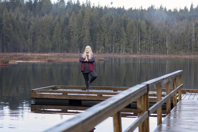 Woman practicing yoga on a lake dock