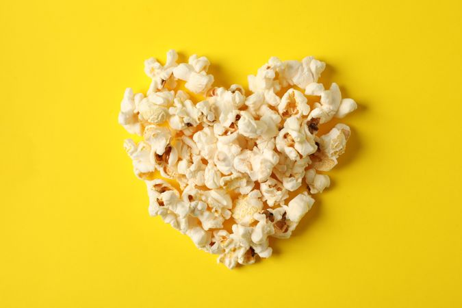 Flat lay composition with popcorn heart on yellow background, space for text