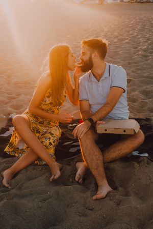 Lovely couple eating together at sandy beach