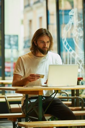 man sitting at table and typing on laptop