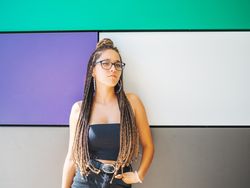 Charming teenage girl with braids in sunglasses nearby colorful wall