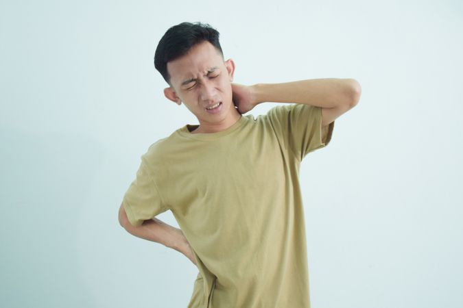 Asian young man touching back of neck and back in pain