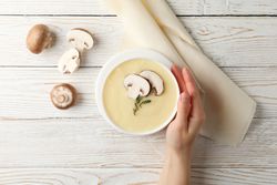 Hand holding a bowl of of creamy soup on table