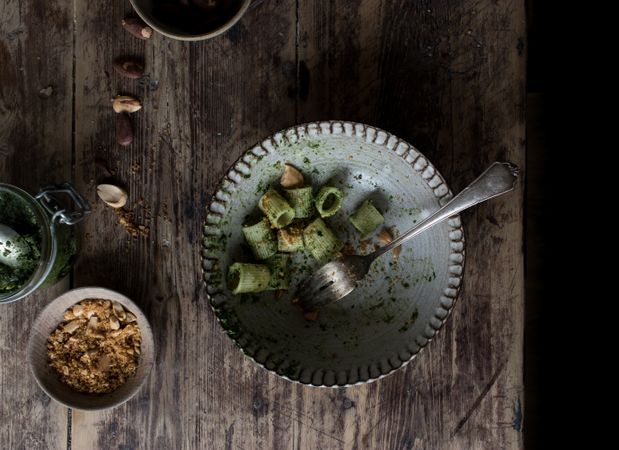Hands taking pasta paccheri with kale pesto and nuts