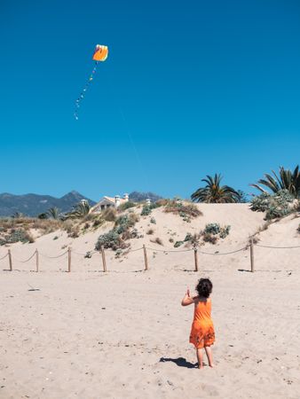Toddler girl playing with kite on sandy beach