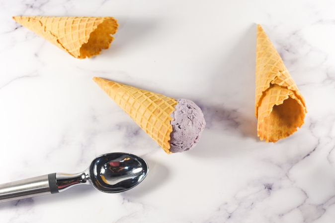 Top view of purple ice cream cone lying on it's side on marble table