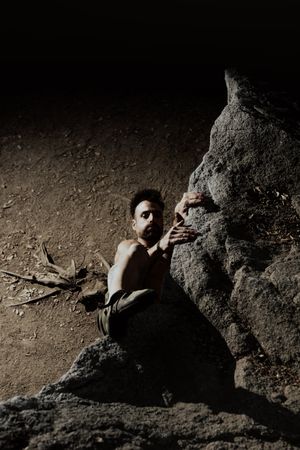 Man practicing rock climbing among large rocks in a forest