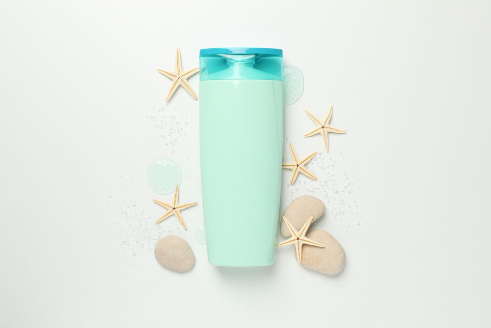 Blank cosmetic bottle and starfishes on light background