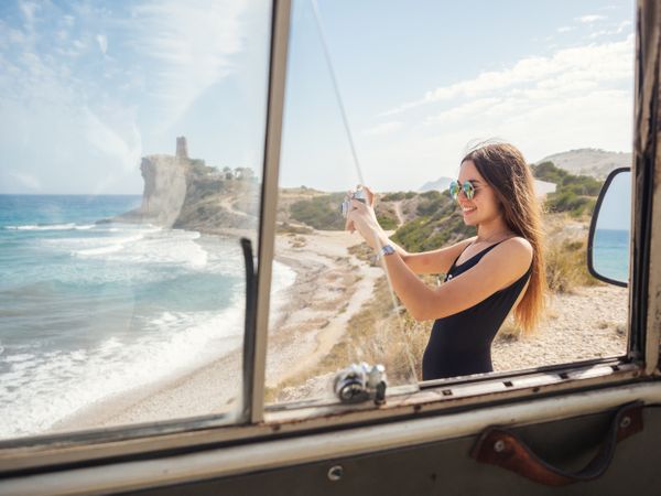 Woman taking photo at rocky coast