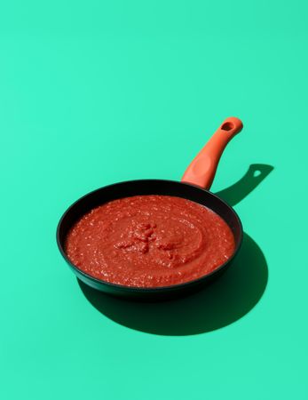 Tomato sauce in an iron pan isolated on a green background