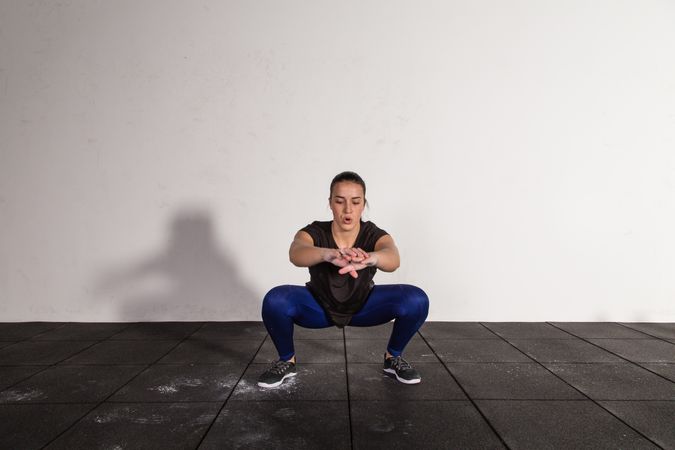 athletic young woman in sportswear doing squats in gym