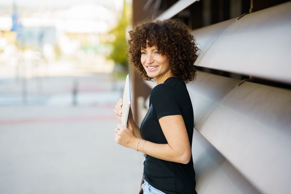An Enthusiastic and Joyful Young Woman with Beautiful Curly Hair Posing Outdoors in Nature
