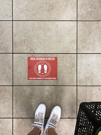 Top view of sign on floor in retail store requesting social distancing