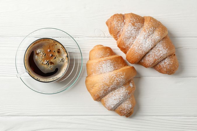 Top view cup of coffee and two croissants on wooden table