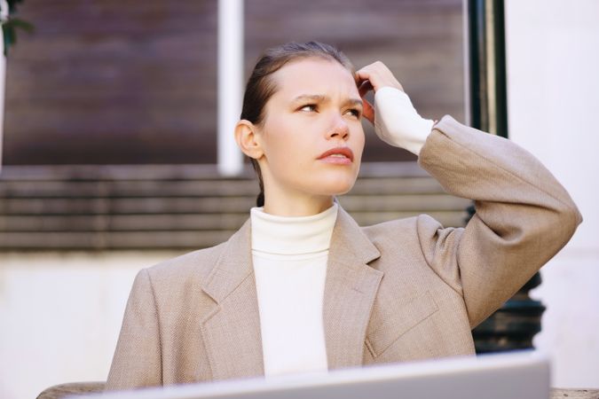 A Thoughtful Young Woman, Dressed in a Chic and Stylish Outfit, is Using a Laptop for Work Purpose