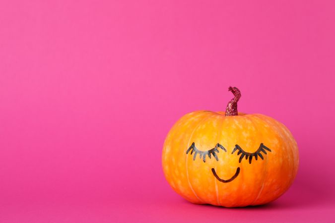 Pumpkin with smile on pink background, space for text