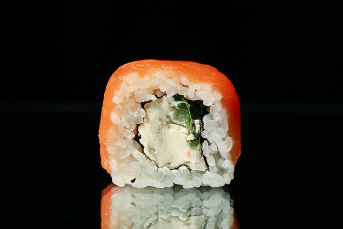 Sushi roll on dark mirror background, close up
