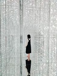Tokyo, Japan - November 19th, 2019: Young woman standing in reflective crystalline installation