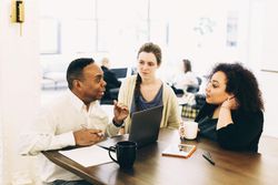 Man and two women sitting and talking in meeting room