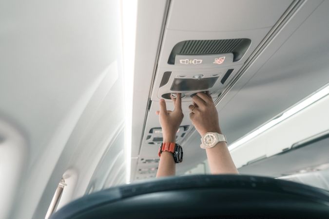 Rear shot of anonymous hands adjusting air vents on an airplane