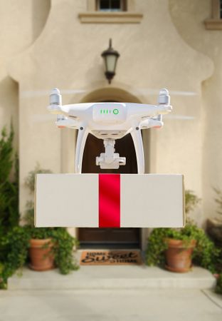 Drone Delivering Red Ribbon Wrapped Package to House Porch