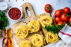 Ingredients for Italian pasta dish on breadboard with copy space