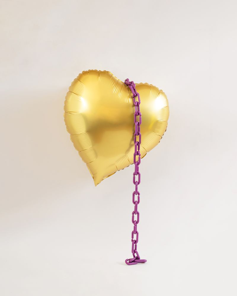 Golden heart balloon in the air with violet purple chains