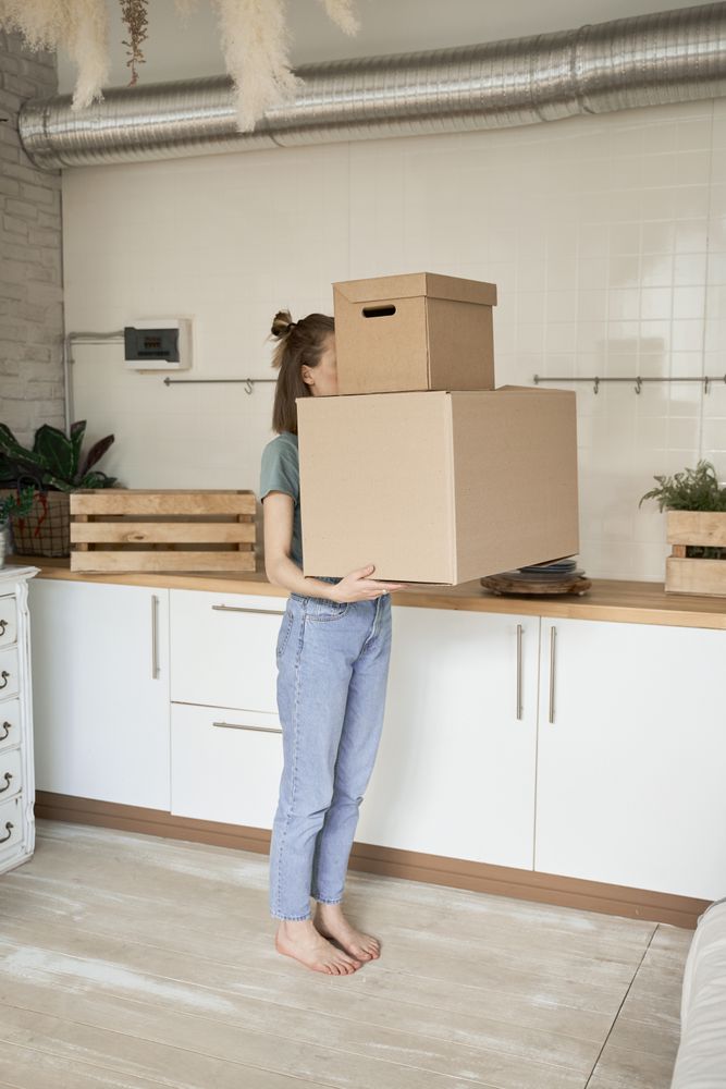 Young woman carrying big carton boxes in house
