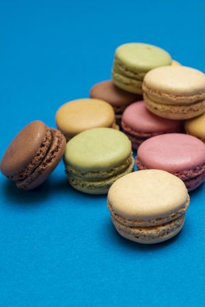 Pile French pastel macaroons on a blue table with copy space