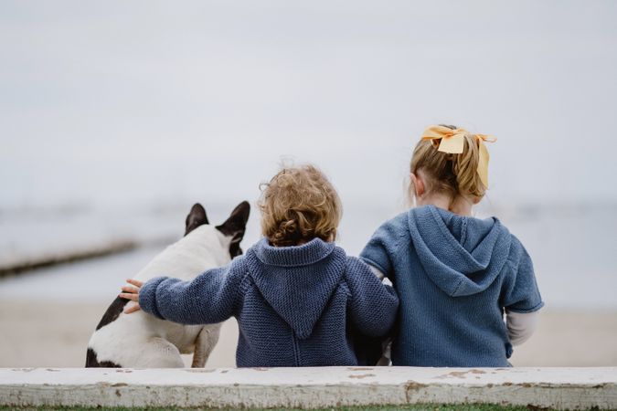 Kids hugging dog on beach