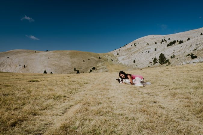 Woman playing with big dog on hill meadow