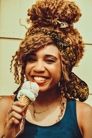 Smiling Black female enjoying an ice cream cone in the sun, vertical