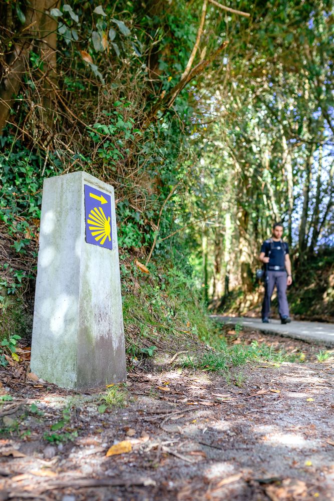 Milestone of Saint James way with pilgrim walking