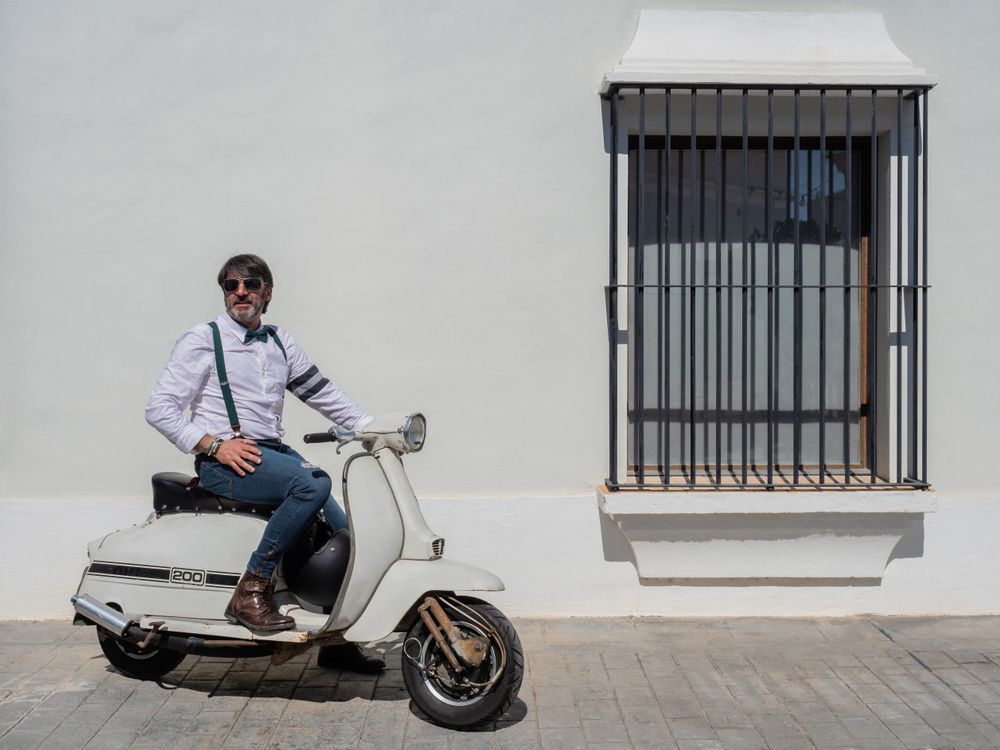 Trendy man sitting on vintage scooter