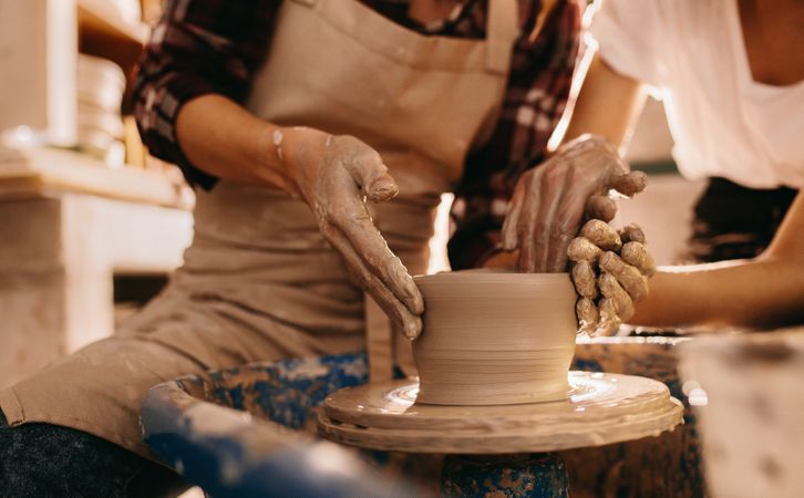 Two women at a pottery workshop making clay pots in studio