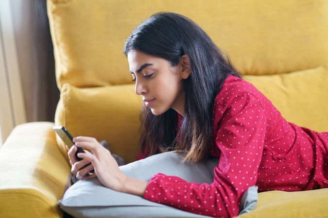 Female relaxing at home while using a smart phone