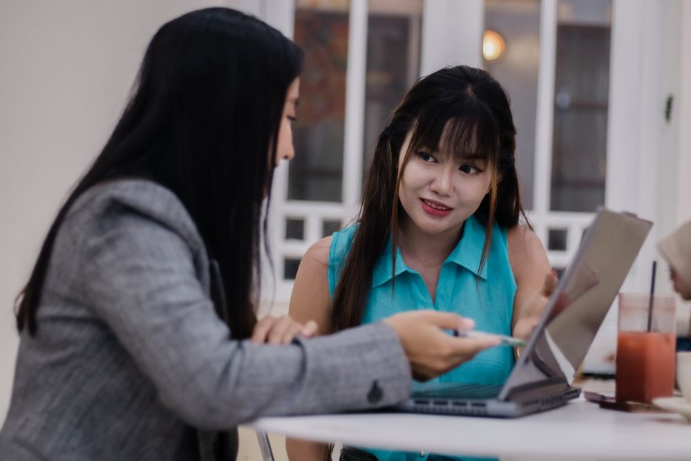 Collaborative Businesswomen Sharing Ideas at Cafe with Laptop
