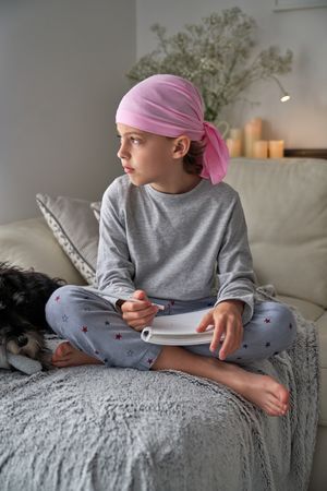 Barefoot boy in pink bandana with notepad thoughtfully looking a