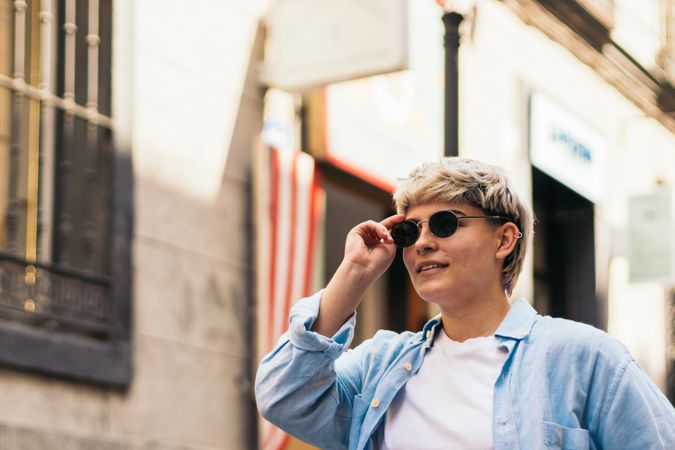 stylish women with short hair putting on the sunglasses while walking