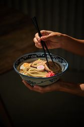 Crop person having traditional ramen soup