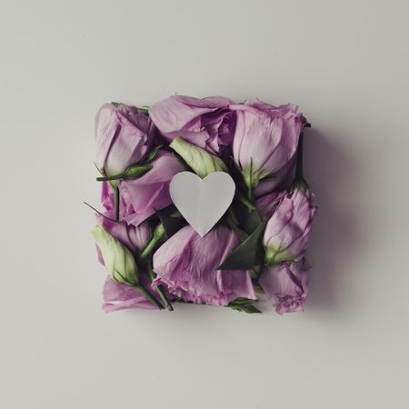 Pink flowers in shape of a gift box with light paper heart on  background