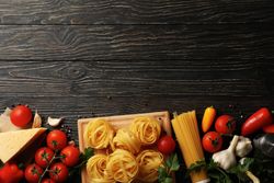 Composition with pasta and ingredients for cooking on wooden background, top view