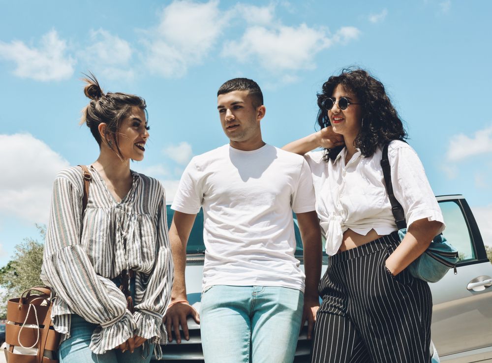 Group of friends enjoying a conversation outside the car.