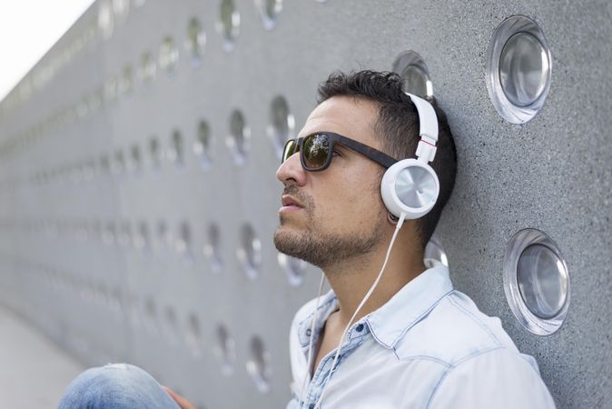 Man leaning back on wall while listening to music