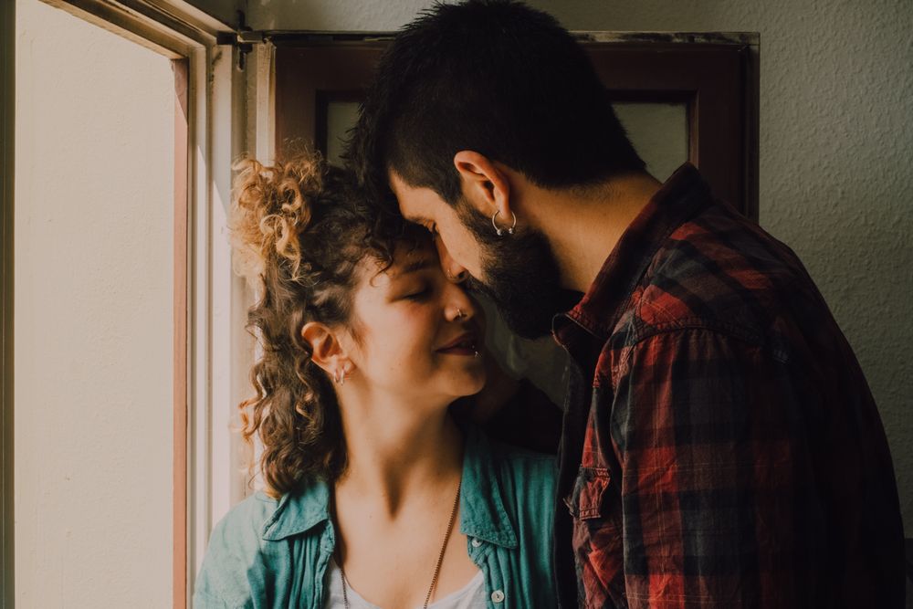 Happy couple embracing on window sill at home