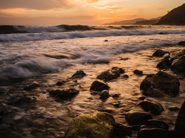 Stony seashore and waves at beautiful sunset