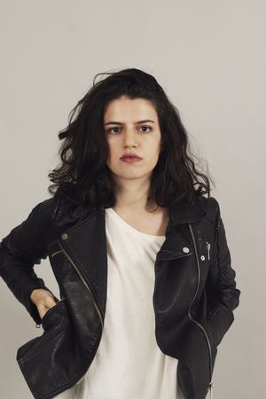 Serious pensive young female wearing leather jacket in studio