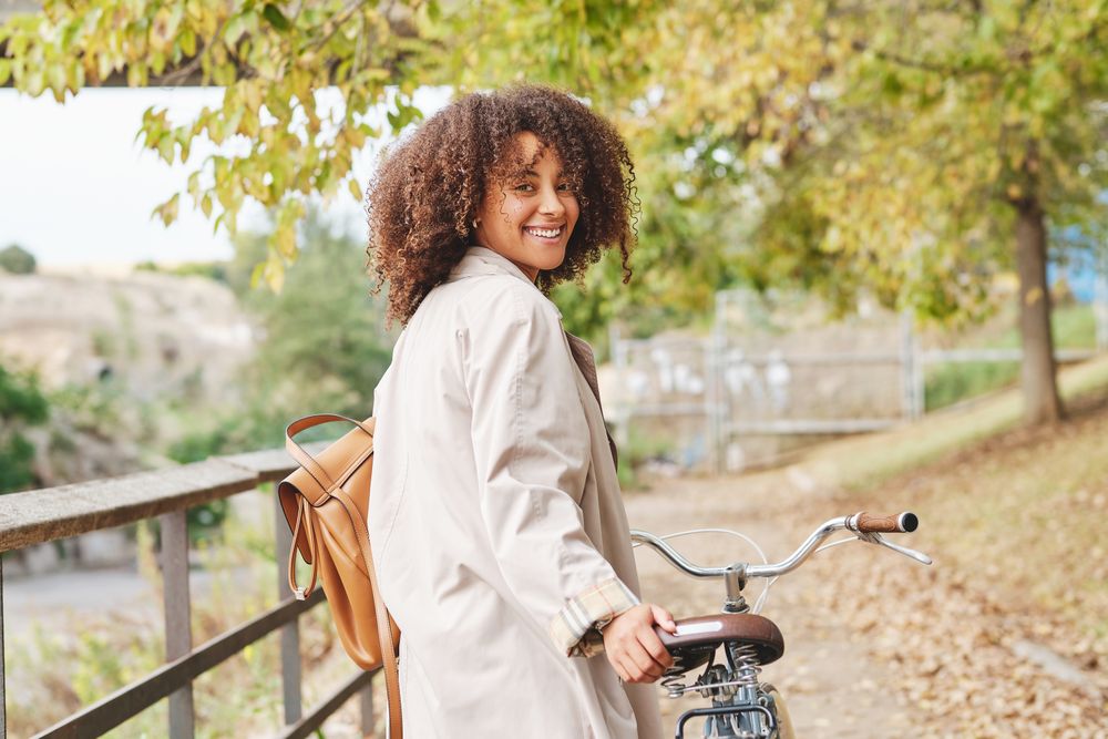 Smiling Black Latina woman with retro bike in autumn day